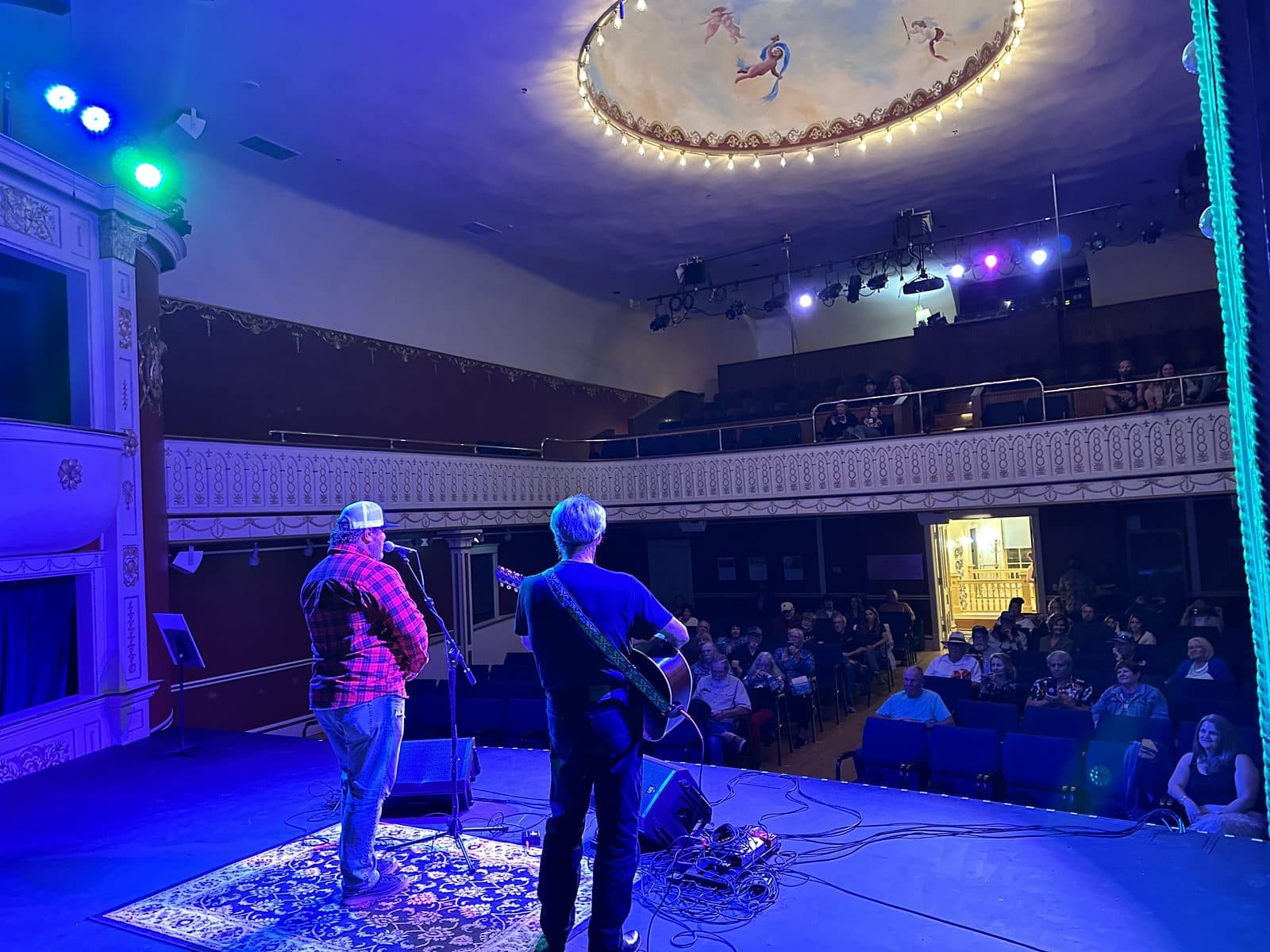 Songwriters performing at the Queen City Songwriters Invitational with an engaged audience